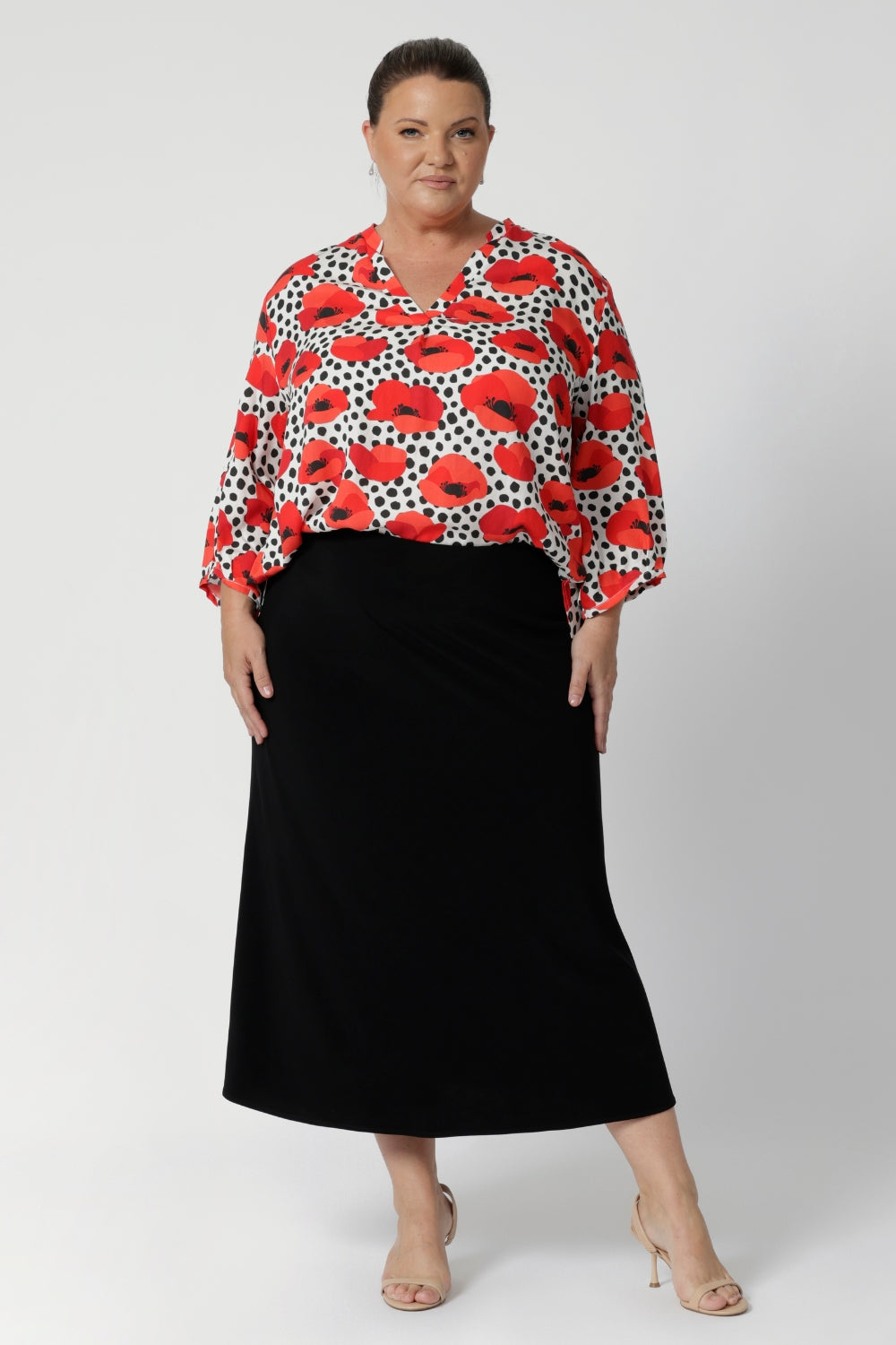 The standout feature of the Kelyn Top is the exaggerated floaty swing back with pleat details, which adds dimension and flow to the piece, creating movement with every step. Plus size woman wears swing shirt with black midi skirt and nude heels for an elevated workwear outfit. Available in sizes 8-24.