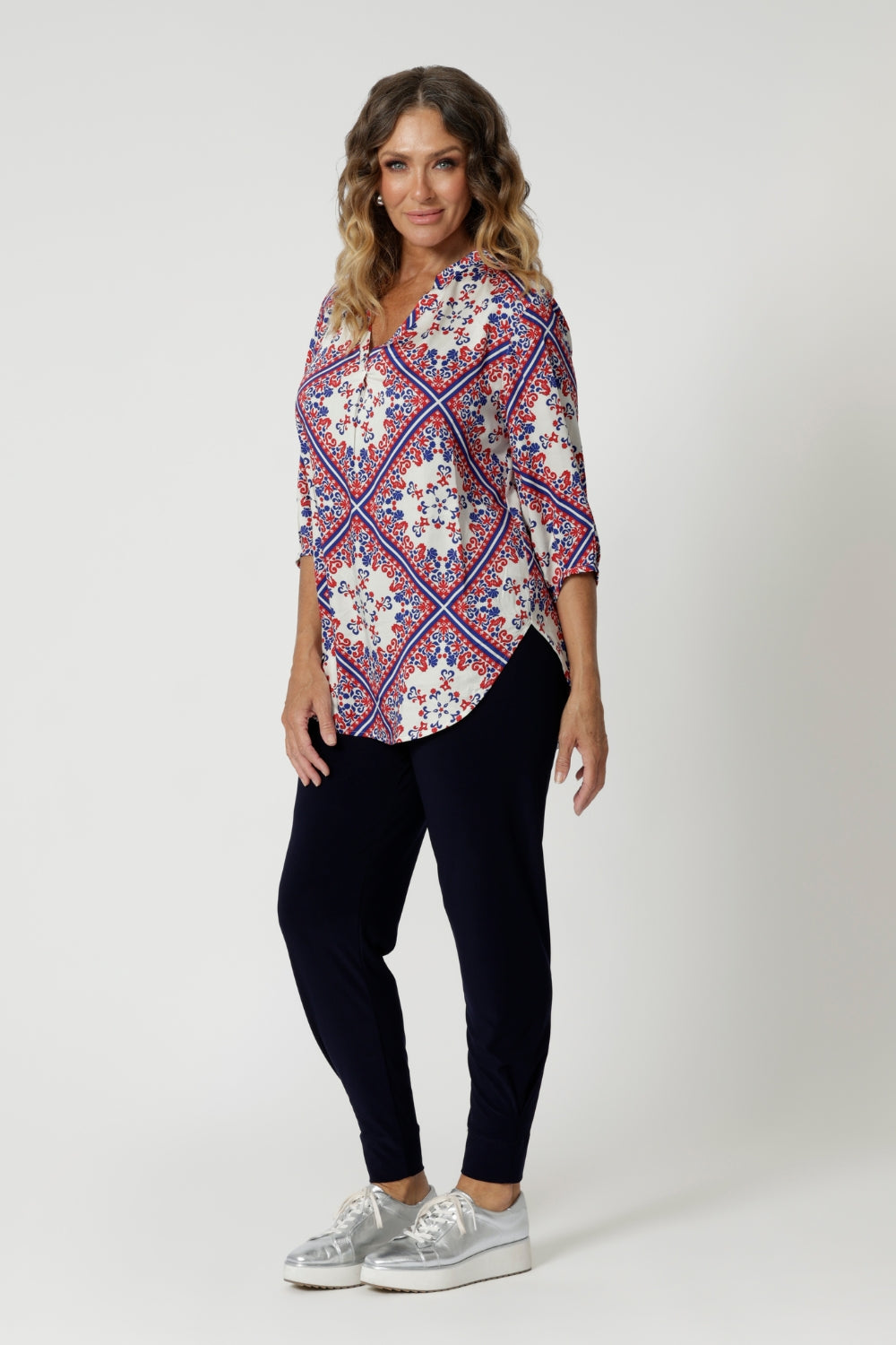 The shirt is designed with a flattering V-neckline that adds a touch of femininity and elongates the neck, making it perfect for warmer weather. The 3/4 sleeves are relaxed and slightly billowy, offering a gentle, airy feel, while the swing-style cut creates a flattering, easy fit that skims over the body, giving the shirt a relaxed yet polished silhouette.