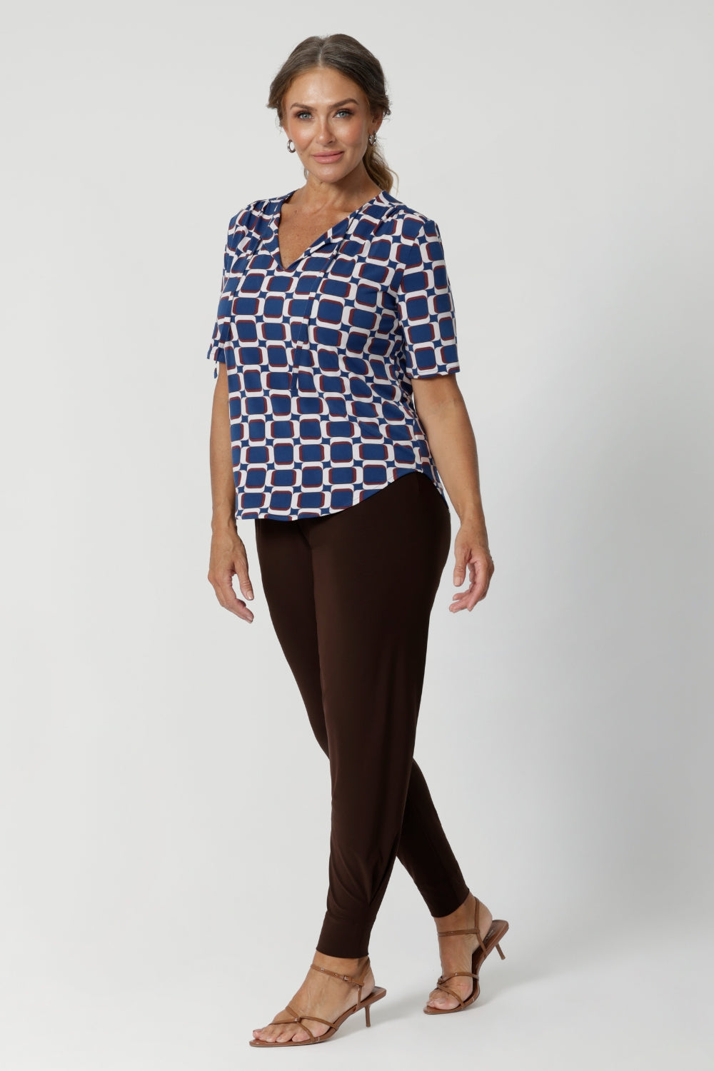 Perfect for the modern woman, the Kodi Top easily transitions from workwear to weekend wear, making it a versatile piece for any occasion. Size 12 model wears printed Kodi Top with matching brown pants and brown kitten heels.