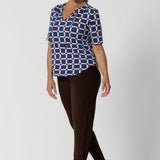 Perfect for the modern woman, the Kodi Top easily transitions from workwear to weekend wear, making it a versatile piece for any occasion. Size 12 model wears printed Kodi Top with matching brown pants and brown kitten heels.