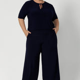 Size 18 model wears elbow sleeve top in navy paired with matching navy pants for an elevated workwear outfit. Available in two elegant colourways. This top also features neck ties that can be adjusted for different looks. Model features neckties tied creating keyhole neckline - for elevated styling. 