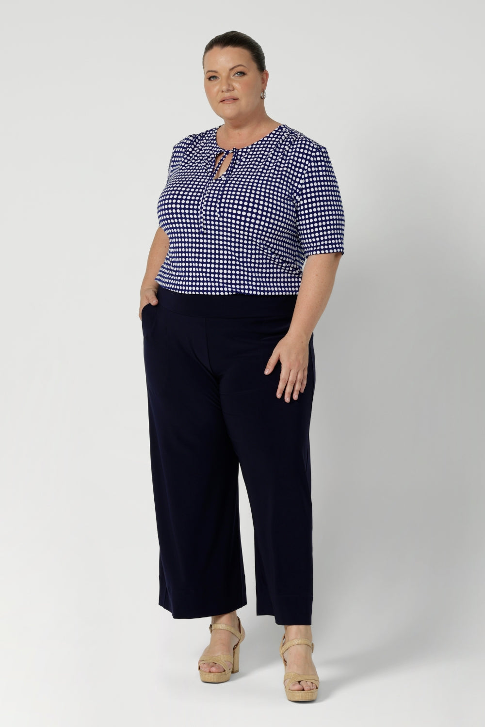 Available in two elegant colourways - polka dot print & classic navy. Size 18 model wears workwear top featuring neck ties that can be adjusted for different looks—either tied for a more tailored effect or left undone for a softer, flowing neckline. Made in Australia and available in sizes 8 to 24.