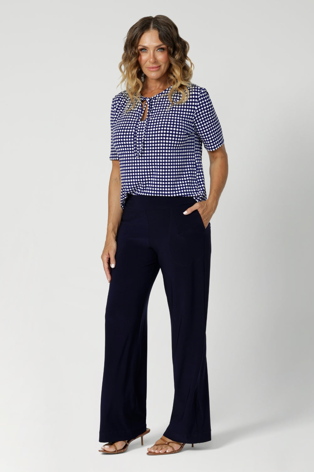 40 year old woman wears tailored work top that can be adjusted for different looks—either tied for a more tailored effect or left undone for a softer, flowing neckline. Versatile and stylish top is available in sizes 8-24.