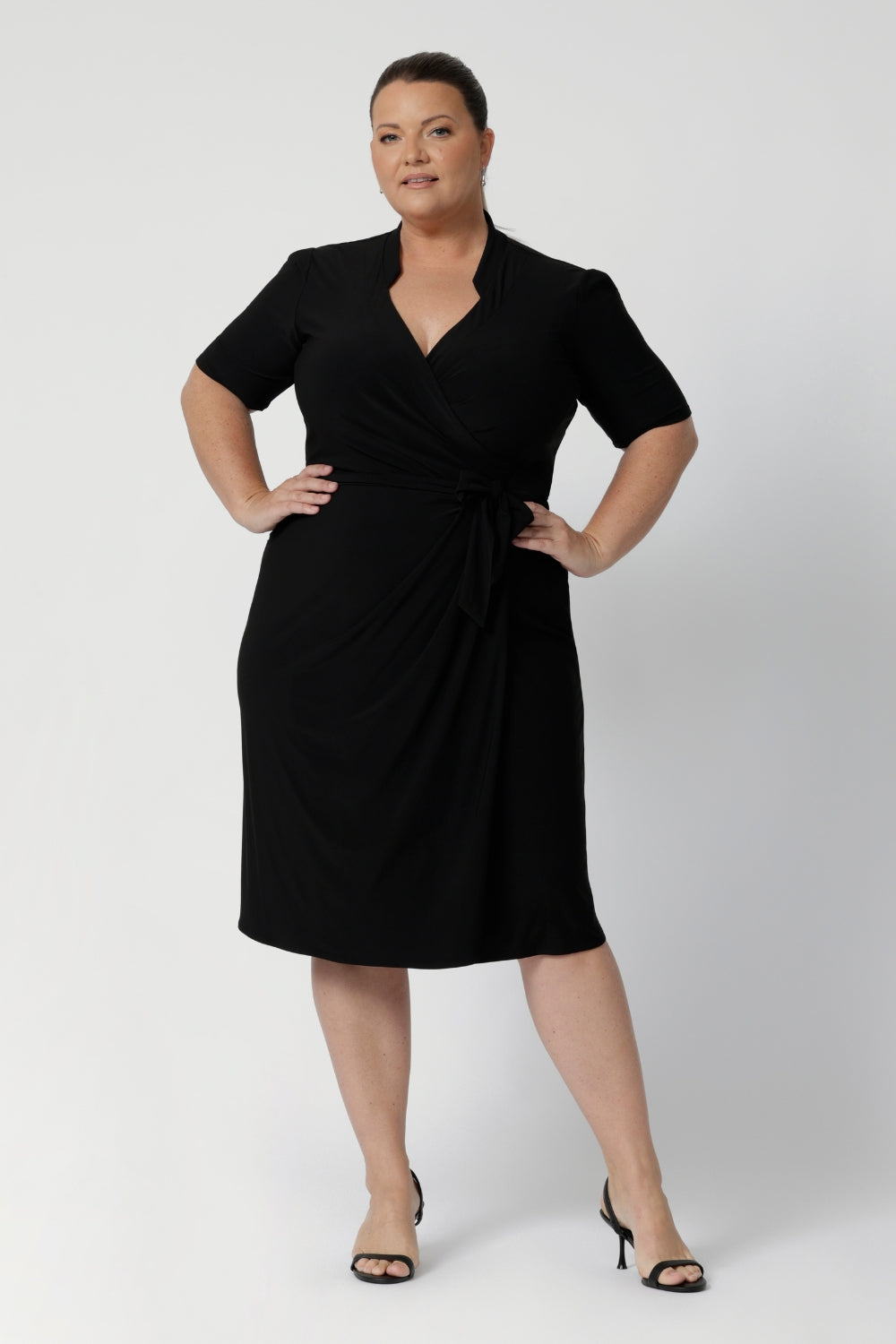 Size 18 woman wears the Kriss dress in black. A functioning wrap work dress in soft black jersey. Great for being comfortable in the office. Made in Australia for women size inclusive fashion 8 - 24.