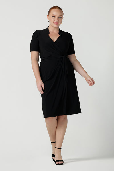 A size 12 woman wears the Kris dress in black. A functioning wrap work dress in soft black jersey. Great for being comfortable in the office. Made in Australia for women size inclusive fashion 8 - 24.