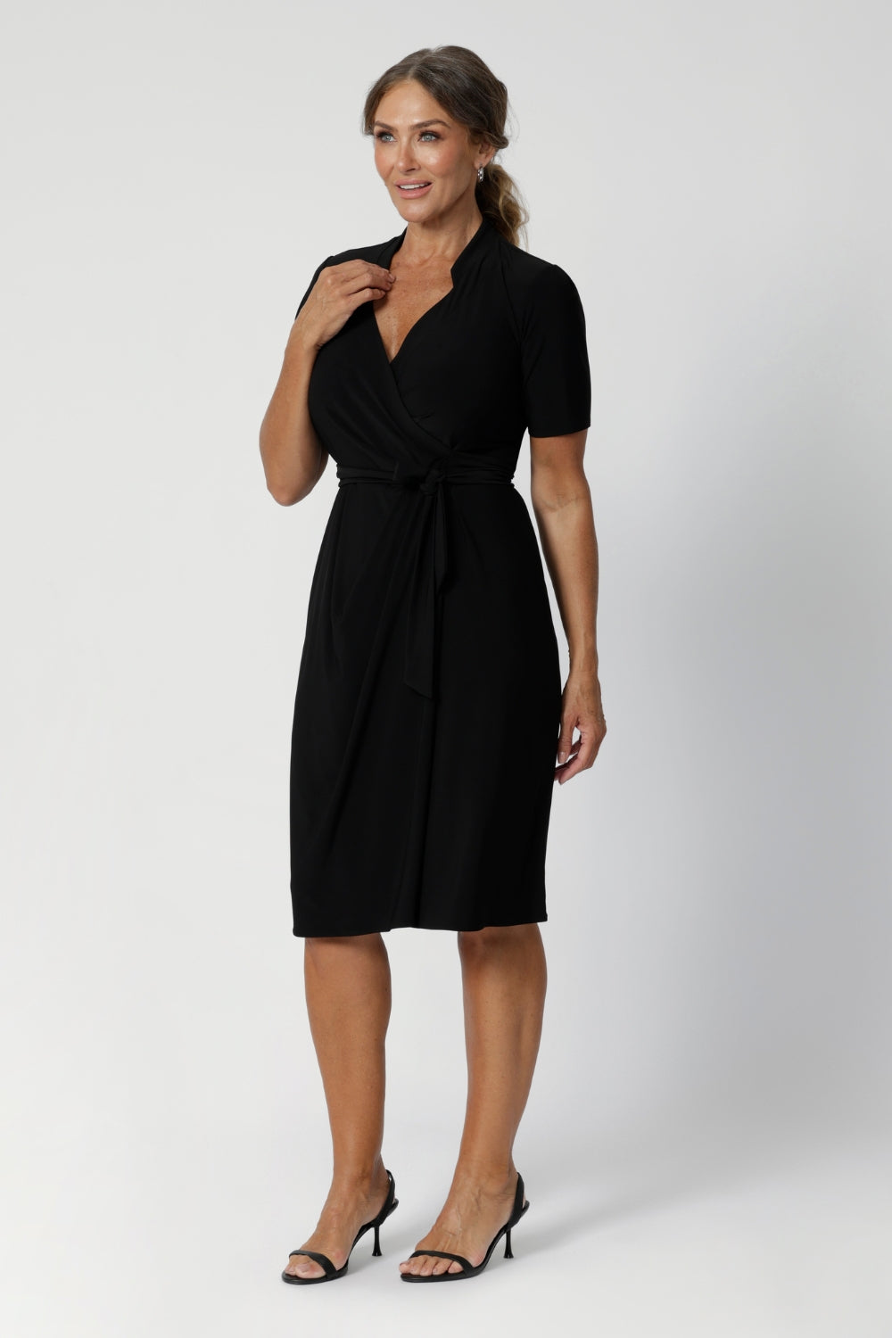 A size 12 woman wears the Kris dress in black. A functioning wrap work dress in soft black jersey. Great for being comfortable in the office. Made in Australia for women size inclusive fashion 8 - 24.