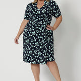 Showing a good wrap dress for plus size women, a size 18, curvy woman wears a short sleeve wrap dress in blue floral print. This easy care, jersey wrap dress is made in Australia by Australian and New Zealand women's clothing brand, Leina & Fleur.