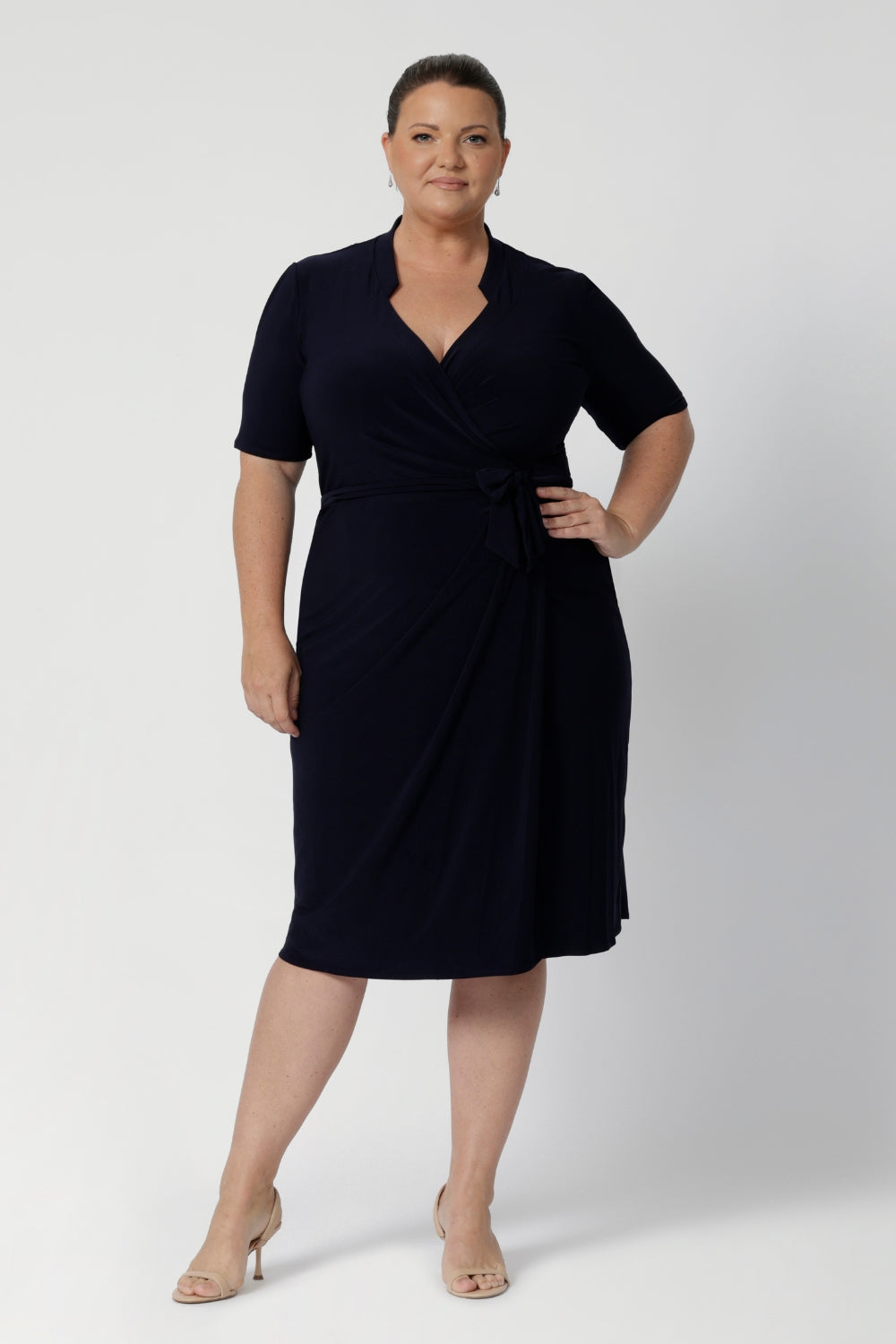 Full body image of a plus sized woman wearing a navy base wrap dress. This collared dress is Australian made for Australian and New Zealand women. Woman’s clothing brand Leina & Fleur stock sizes from 8 to 24 including plus sizes and petite sizes. 