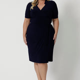 Full body image of a plus sized woman wearing a navy base wrap dress. This collared dress is Australian made for Australian and New Zealand women. Woman’s clothing brand Leina & Fleur stock sizes from 8 to 24 including plus sizes and petite sizes. 