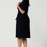 Side view of a Kade dress in Navy is a functioning wrap dress in navy. Featuring a mandarin collar and short sleeves. Gathered at the waist with a functioning tie. Made in Australia for women size 8 - 24.