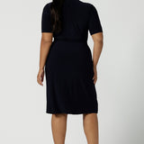 Back view of Kade dress in Navy A size 16 is a functioning wrap dress in navy. Featuring a mandarin collar and short sleeves. Gathered at the waist with a functioning tie. Made in Australia for women size 8 - 24.