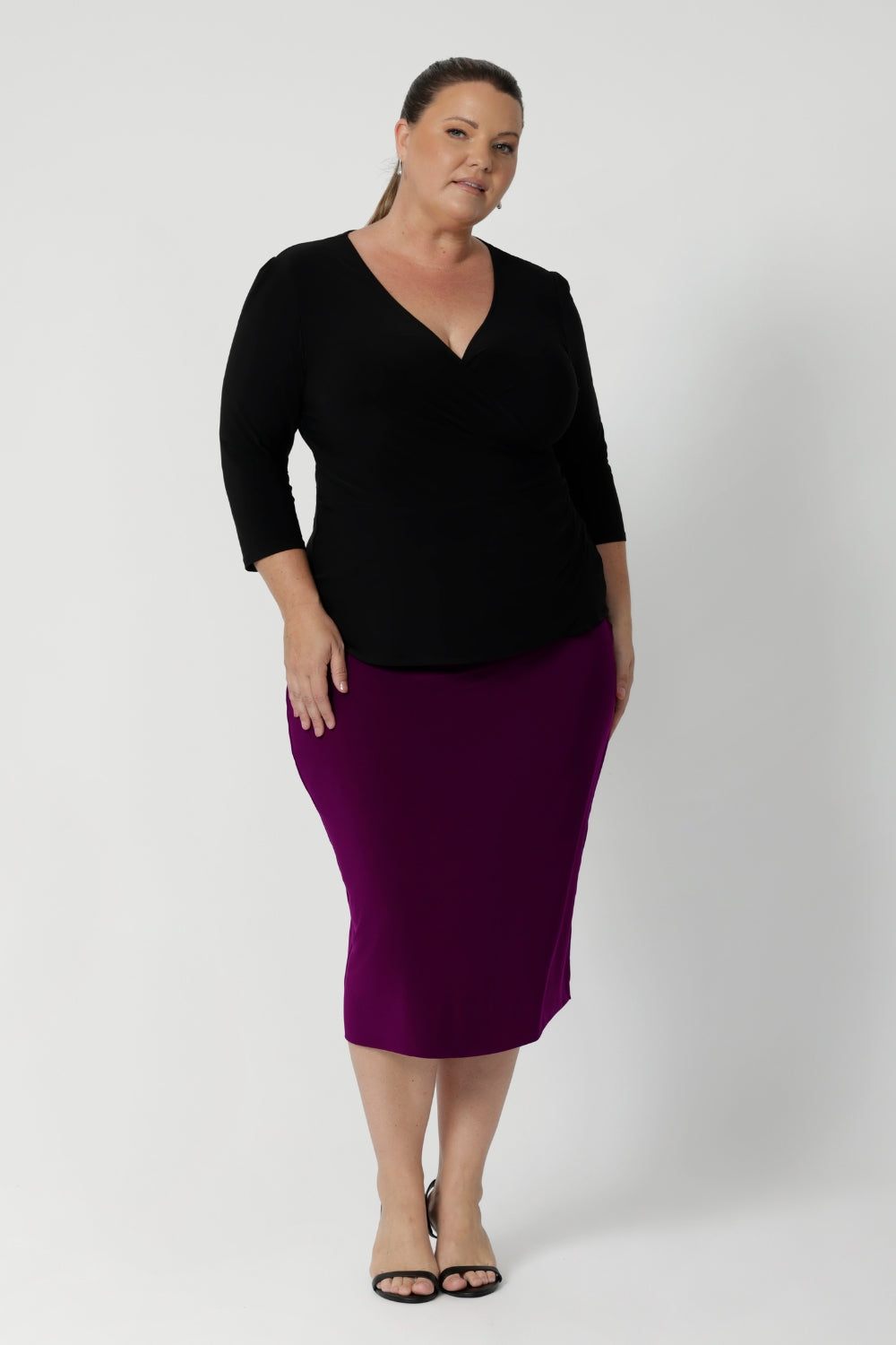 Size 18 woman wears the Kyle top in Black. A soft wrap top made in Australia for women size 8 - 24. The perfect work to weekend top in comfortable and easy care jersey.