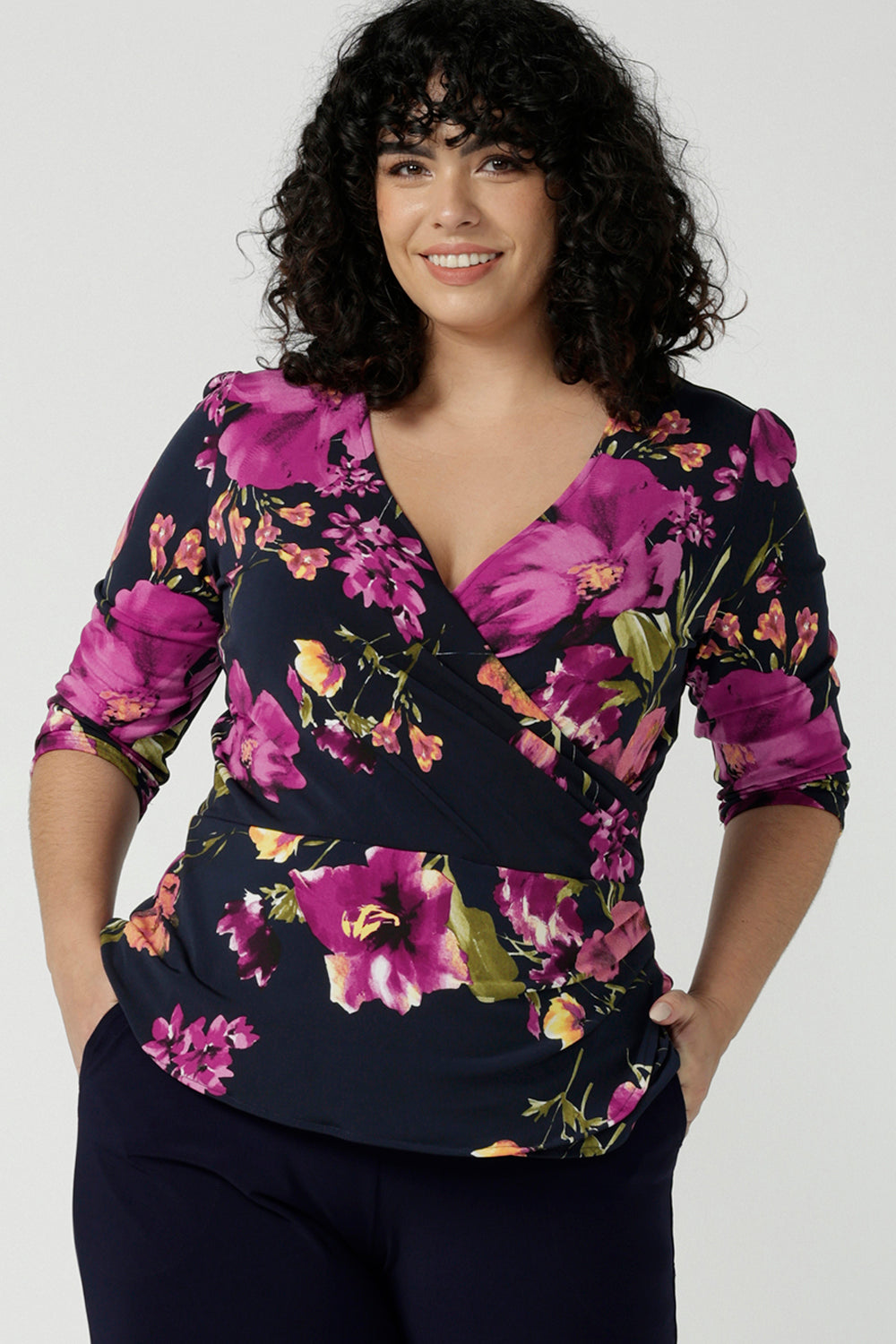 Size 18 woman wears the Celeste Top  and Navy monroe pant. A beautiful fixed wrap top with a peplum and shoulder sleeeve tuck with 3/4 sleeves. Made in Australia for women size 8 - 24. 