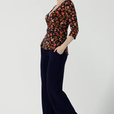 Side view of a Kyle Top in Lava is a functioning wrap to in jersey fabric with animal print. Styled back with Monroe Pant in black. Made in soft jersey fabric and made in Australia for women size 8 - 24.