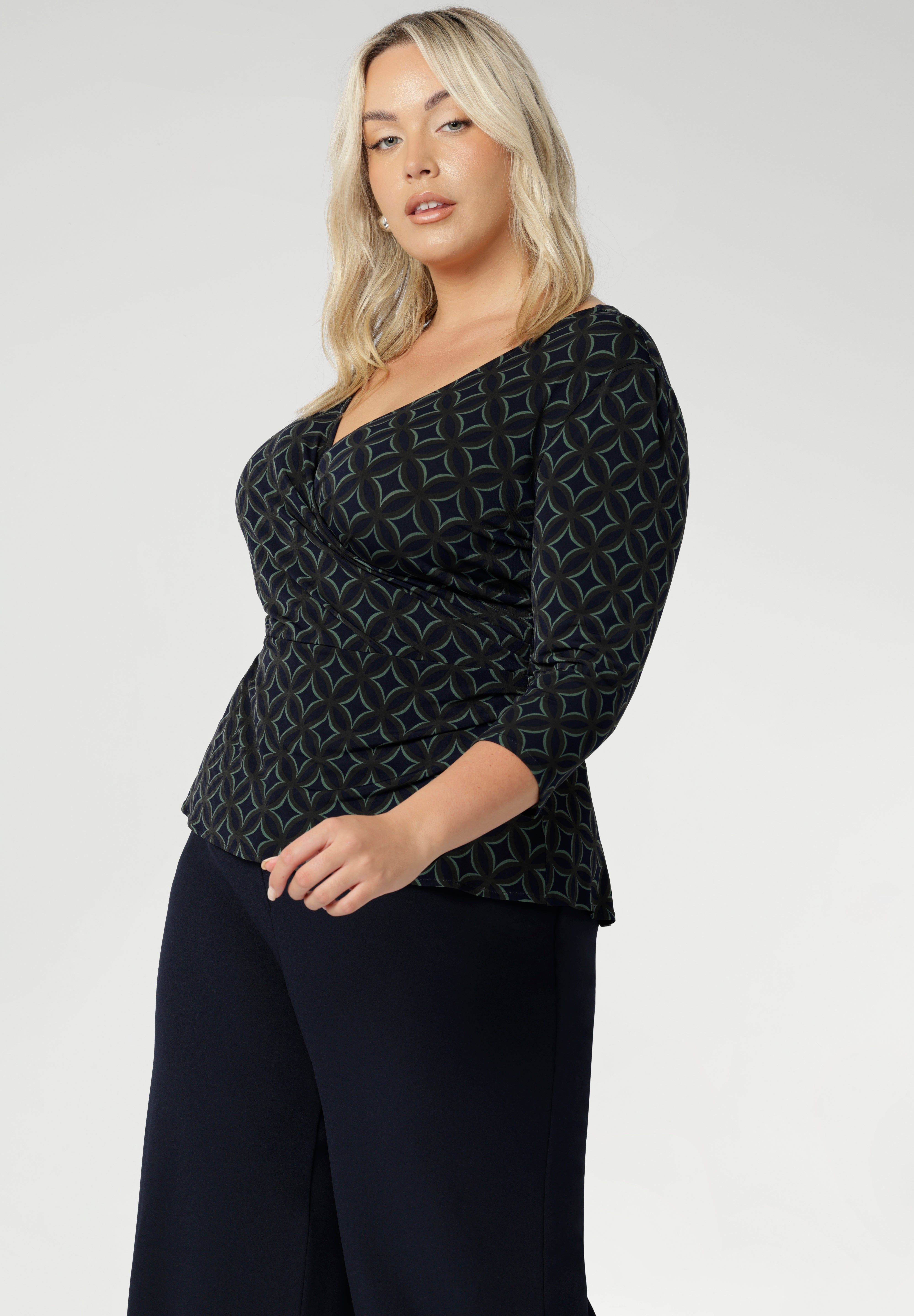 The double-layer back bodice adds extra structure, while the 3/4 length sleeves offer an elegant touch. Proudly made in Australia, the Kyle Top is available in sizes 8 to 24, designed to flatter both petite and plus-size women. Size 18 woman wears her Kyle Top over some Navy Workwear pants. 