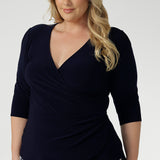 A Size 18 model wears the Kyle Top in Navy made in Australia for women size 8 - 24.  A fixed wrap top in Navy with 3/4 sleeves and a fixed wrap. Pleated from and v-neckline. A versatile work to dinner date top. Made in Australia for women size 8-24. 