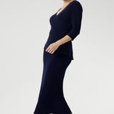Whether you're in the office or heading to after-work events, the Kyle Top delivers confidence and style with ease. Size 10 model wears navy wrap top with navy midi  skirt and black boots for a faux dress look.