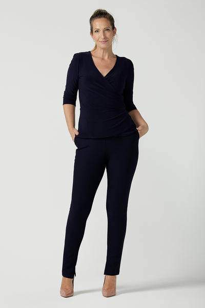 A size 10 model wears the Kyle Top in Navy made in Australia for women size 8 - 24. A fixed wrap top in Navy with 3/4 sleeves and a fixed wrap. Pleated from and v-neckline. A versatile work to dinner date top. Made in Australia for women size 8 - 24. Styled back with Navy Brooklyn pants. 