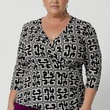 Plus size woman wears 3/4 length sleeve top. Workwear shirt offers coverage and comfort while maintaining a refined, sophisticated silhouette. Size 18 woman pairs her printed top with magenta coloured skirt.