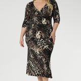 The Kyle Top in Panthera—a bold cheetah print—features a fixed wrap bodice that stays perfectly in place, offering the elegance of a wrap design without the need for constant adjustment. Size 18 woman wears her Kyle Top Over her Asher  Skirt in Panthera. 