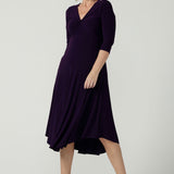 Size 10 Woman wears the Amethyst Kyra dress in jersey. Made in Australia for women. Beautiful twist front neckline with 3/4 sleeve, high-low hem, empire line. Work wear for women and easy care. Great wedding guest outfit, mother of the bride. Made in Australia for women size 8 - 24.