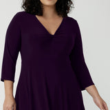 Close up of a size 18 Woman wears the Amethyst Kyra dress in jersey. Made in Australia for women. Beautiful twist front neckline with 3/4 sleeve, high-low hem, empire line. Work wear for women and easy care. Great wedding guest outfit, mother of the bride. Made in Australia for women size 8 - 24.