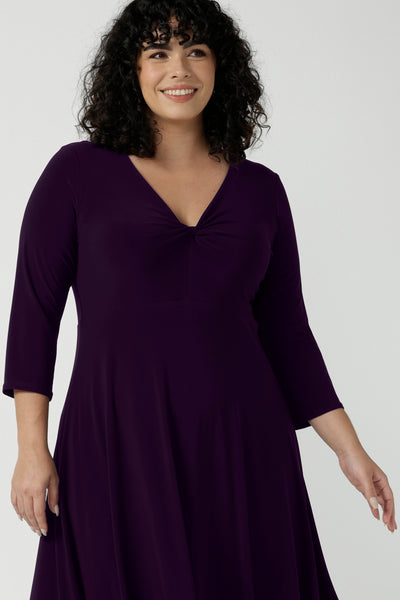 Close up of a size 18 Woman wears the Amethyst Kyra dress in jersey. Made in Australia for women. Beautiful twist front neckline with 3/4 sleeve, high-low hem, empire line. Work wear for women and easy care. Great wedding guest outfit, mother of the bride. Made in Australia for women size 8 - 24.