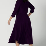 Back view of a size 18 Woman wears the Amethyst Kyra dress in jersey. Made in Australia for women. Beautiful twist front neckline with 3/4 sleeve, high-low hem, empire line. Work wear for women and easy care. Great wedding guest outfit, mother of the bride. Made in Australia for women size 8 - 24.