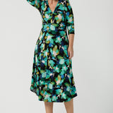 A size 8 woman wears the Kyra dress in Canopy. A twist front dress with a 3/4 sleeve on a watercolour print. Made in Australia for women size 8 - 24.