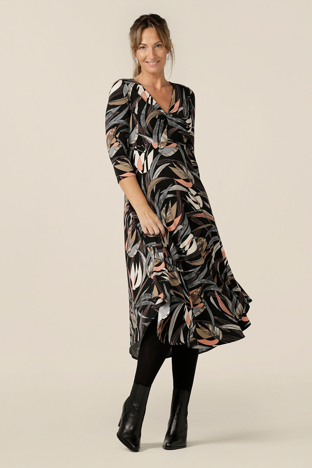 A size 10 woman wears an empire line dress with sweetheart neckline and 3/4 sleeves. Great Australian-made work wear, this twist front dress with midi-length skirt is an elegant office dress.