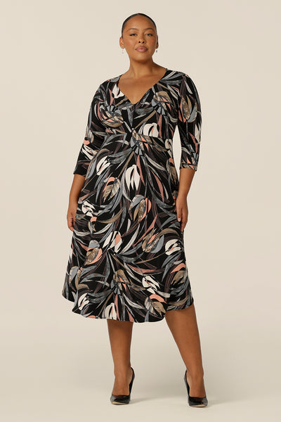 A fuller figure, size 18 woman wears an empire line dress with sweetheart neckline and 3/4 sleeves. Great for work wear, this mid-length  dress with sleeves looks smart for office dress style.