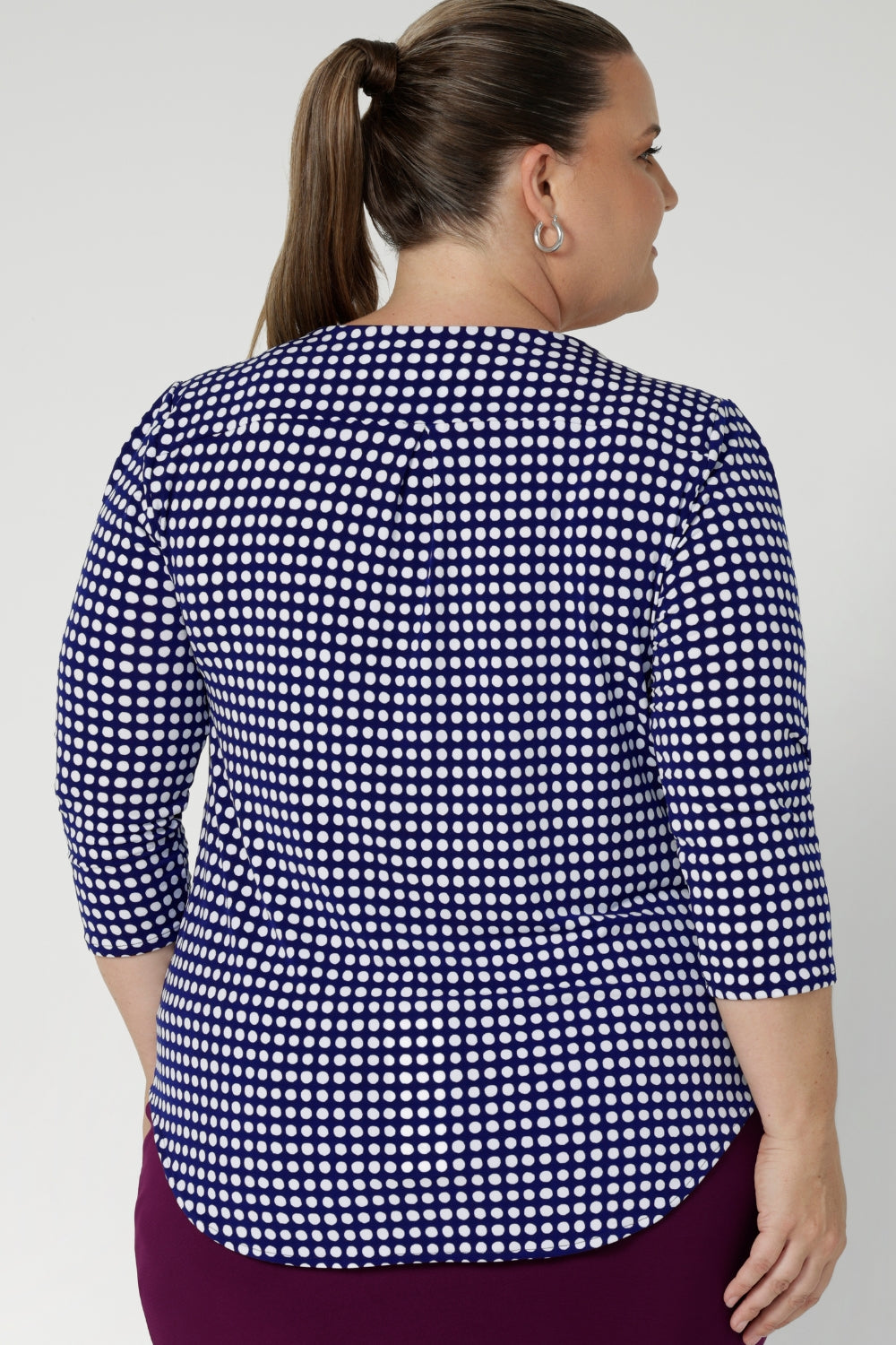 Close up image of plus size model wears workwear top that features curved shirt-tail hemline that gives this top a polished, contemporary finish, offering versatility for both tucked and untucked styles. Sizes 8-24 available.