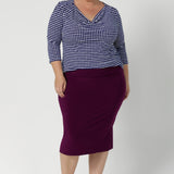 Plus size woman wears her Kyrie Top in Polka Dot untucked with a magenta coloured tube skirt and brown kitten heels.  This cowl neck top matches with many colours and is a versatile styling piece for the working woman. Available in sizes 8-24.