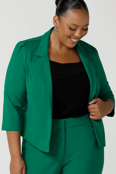 A curvy size 18 woman wears a tailored jacket with open front and collar and notch lapels is made in Emerald green ponte fabric. Shop exclusive luxury, this work jacket is available to pre-order at Australian and New Zealand women's clothing label, L&F.
