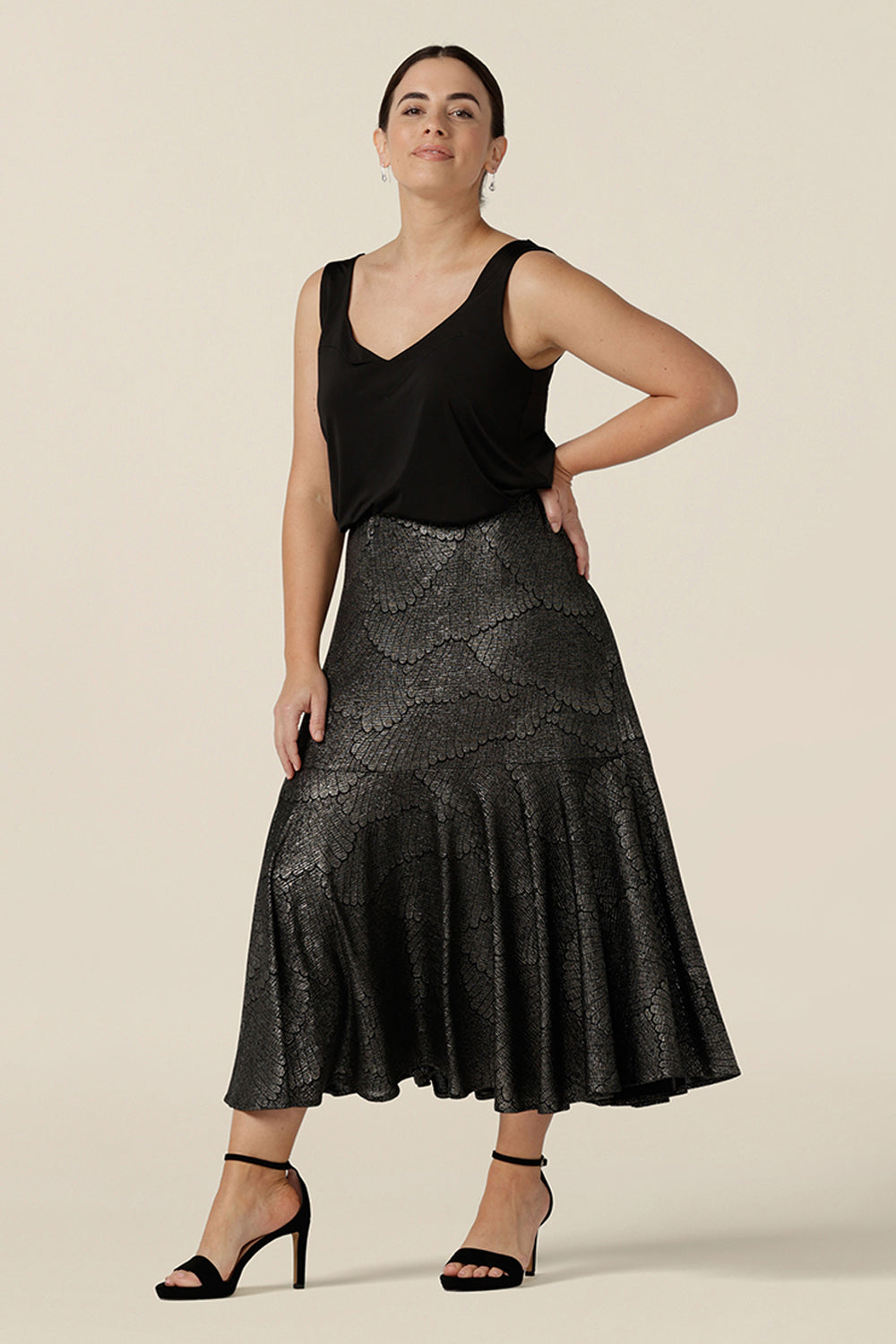 A size 10, petite height woman wears a midi length, foil print evening skirt with ruffle hem. Styled with a black cami top as a cocktail wear outfit, both are made in Australia by women's fashion brand, Leina & Fleur. Shop evening and cocktail wear online in sizes 8 to 24.