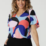 A size 10 woman wears the Lila Top in Amalfi. A jersey tpoo with flutter sleeves and an abstract print. Made in Australia for women size 8-24