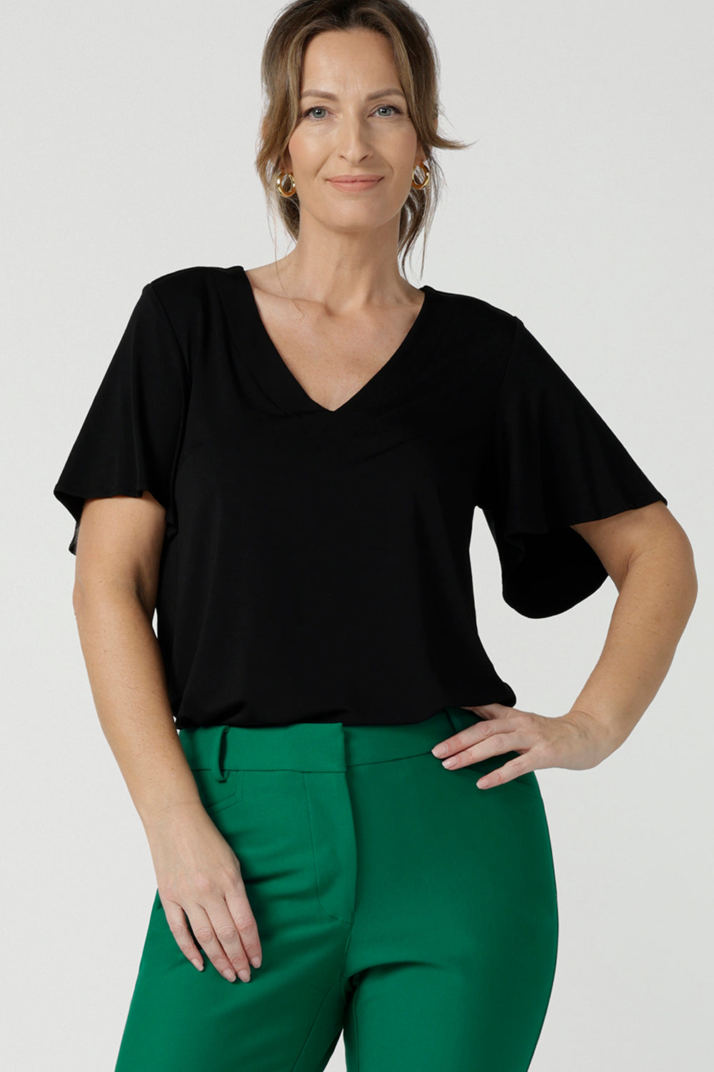 A flutter sleeve, black top for work and casual wear, this tailored top is worn by a size 10, 40 plus woman. Made in Australia, shop women's black tops online at Australian and New Zealand women's clothing brand, Leina & Fleur.