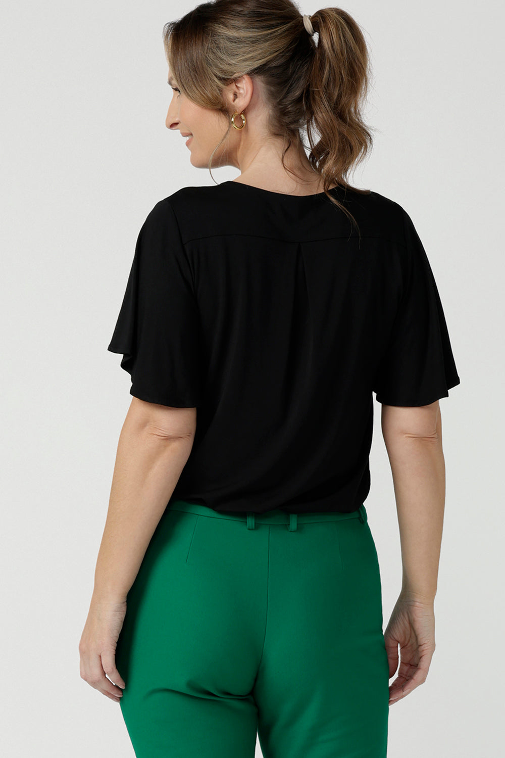 Back view of a flutter sleeve, black top for work and casual wear, this tailored top is worn by a size 10, 40 plus woman. Made in Australia, shop women's black tops online at Australian and New Zealand women's clothing brand, Leina & Fleur.