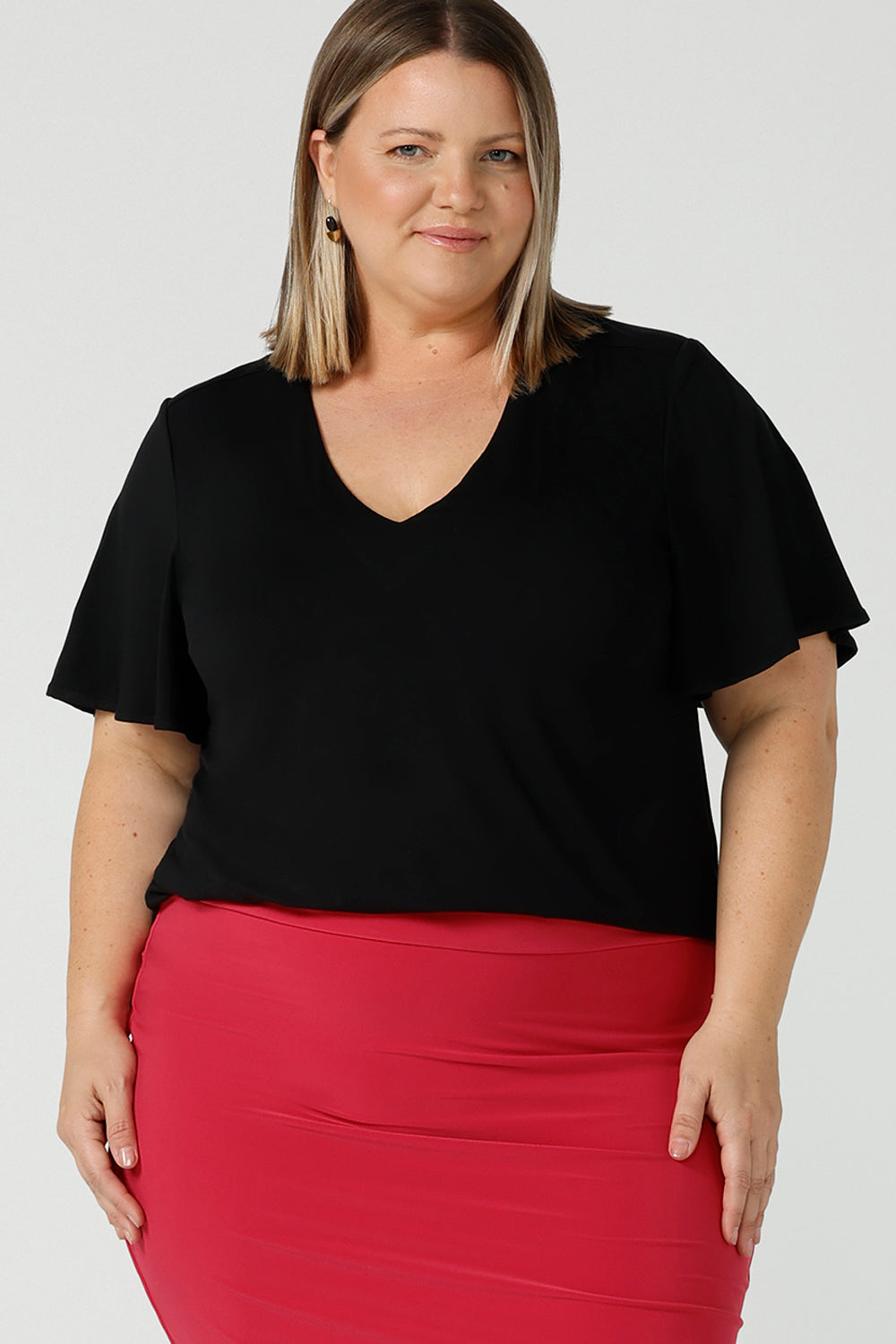 Close up of a flutter sleeve, black top for work and casual wear, this tailored top is worn by a size 18 curvy woman. Made in Australia, shop women's black tops online at Australian and New Zealand women's clothing brand, Leina & Fleur.