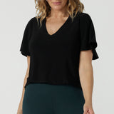 A size 10 woman wears the Lila Top in Black, a jersey workwear top for women for flutter sleeve and v-neckline. Made in Australia for women size 8-24.