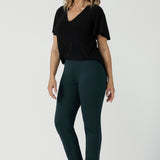 Back view of a size 10 woman wears the Lila Top in Black, a jersey workwear top for women for flutter sleeve and v-neckline. Made in Australia for women size 8-24. Styled back with a Paxton Pant in Alpine. 