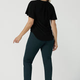 Back view of a size 10 woman wears the Lila Top in Black, a jersey workwear top for women for flutter sleeve and v-neckline. Made in Australia for women size 8-24. Styled back with a Paxton Pant in Alpine.