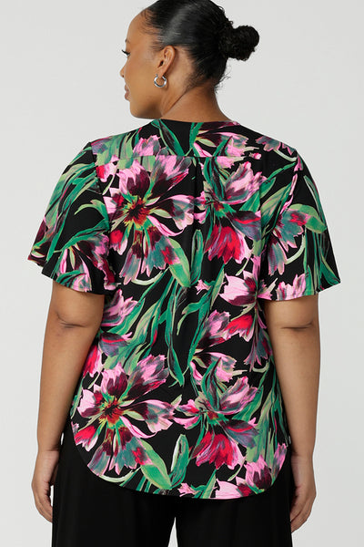 Back view of a plus size, size 18 woman wearing a floral print jersey, V-neck top with flutter sleeves. A good top for summer casual wear, or style tucked as a workwear top. Shop made in Australia tops in petite to plus sizes online at Australian fashion brand, Leina & Fleur.