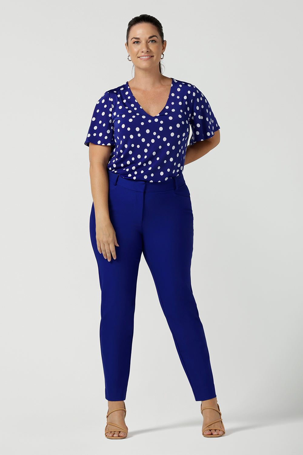 Lila top in Cobalt Spot on a happy size 12 woman. Curved hemline and flutter sleeves. A abstract polka dot print. Made in Australia for women size 8 to 24.