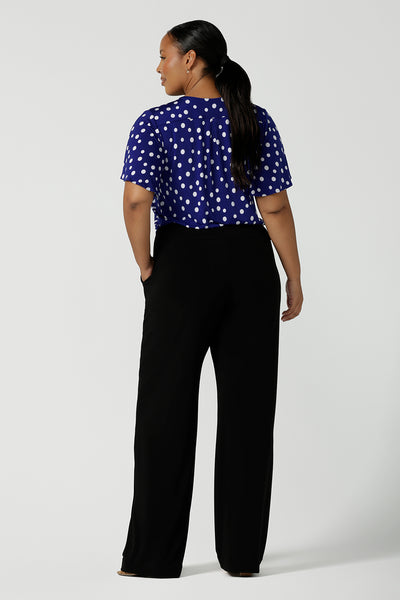 Back view of the Lila Top in Cobalt spot, V-Neckline with flutter sleeves and a curved hemline. Styled back with black Monroe Pants. Comfortable corporate wear for women.Solf silky jersey and made in Australia for women size 8 - 24.