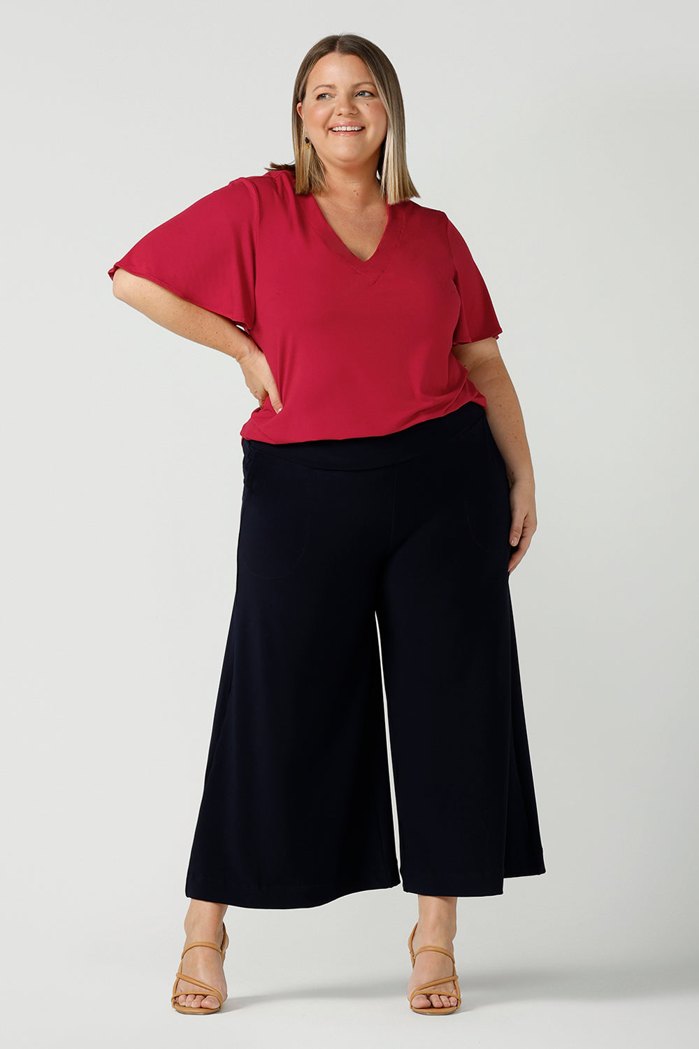 Happy curvy woman wears the Lila Top in Flame bamboo in a Christmas red colour. The bamboo material is breathable, soft and temperature regulating. The Lila top features a flutter sleeve and deep v-neckline. Made in Australia for women size 8-24.