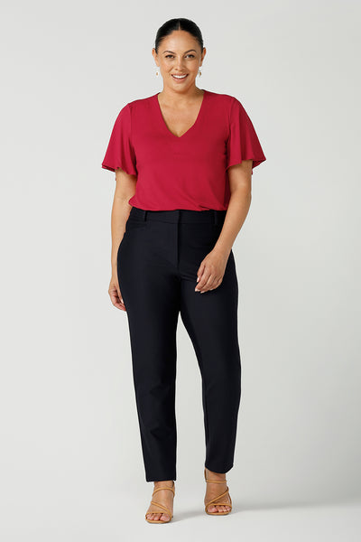 Happy size 12 woman wears the Lila Top in Flame bamboo in a Christmas red colour. The bamboo material is breathable, soft and temperature regulating. The Lila top features a flutter sleeve and deep v-neckline. Made in Australia for women size 8-24.