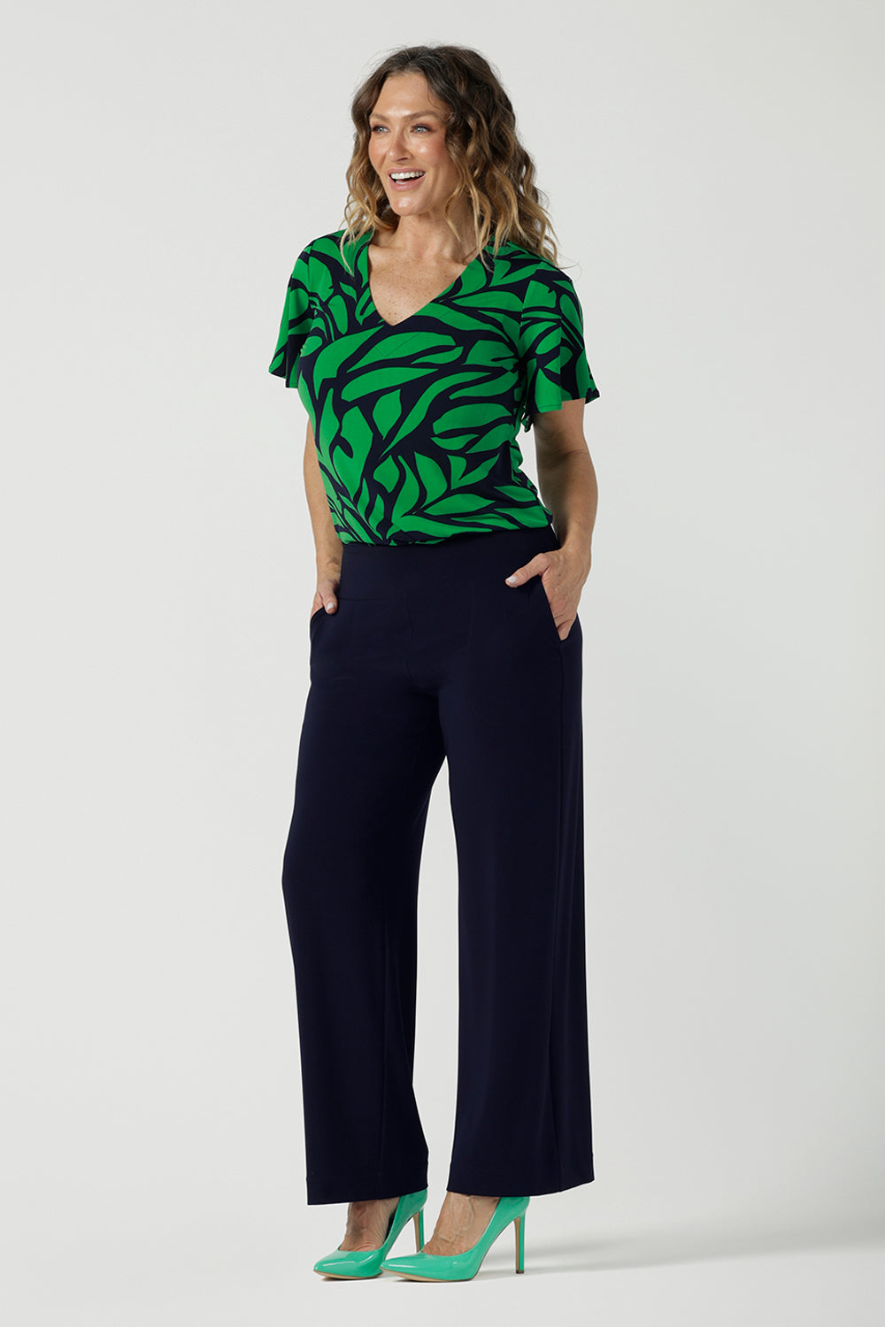 A size 10 woman wears the Lila Top in Green Jungle. Made in Australia style for women size 8-24. Comfortable jersey fabric and easy care. Flutter sleeve with V-Neckline.