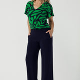 A size 10 woman wears the Lila Top in Green Jungle. Made in Australia style for women size 8-24. Comfortable jersey fabric and easy care. Flutter sleeve with V-Neckline.