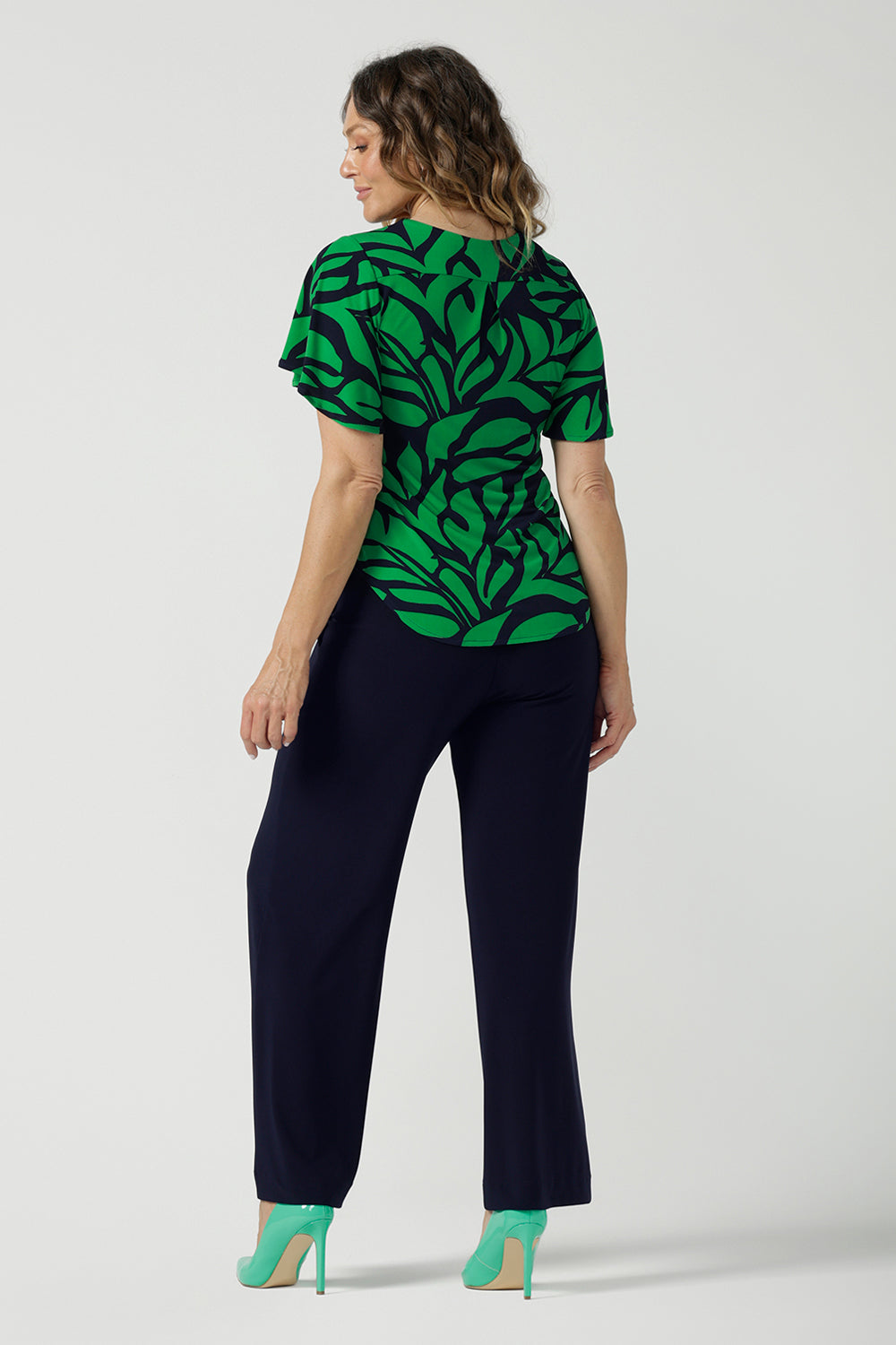 Back view of a size 10 woman wears the Lila Top in Green Jungle. Made in Australia style for women size 8-24. Comfortable jersey fabric and easy care. Flutter sleeve with V-Neckline.